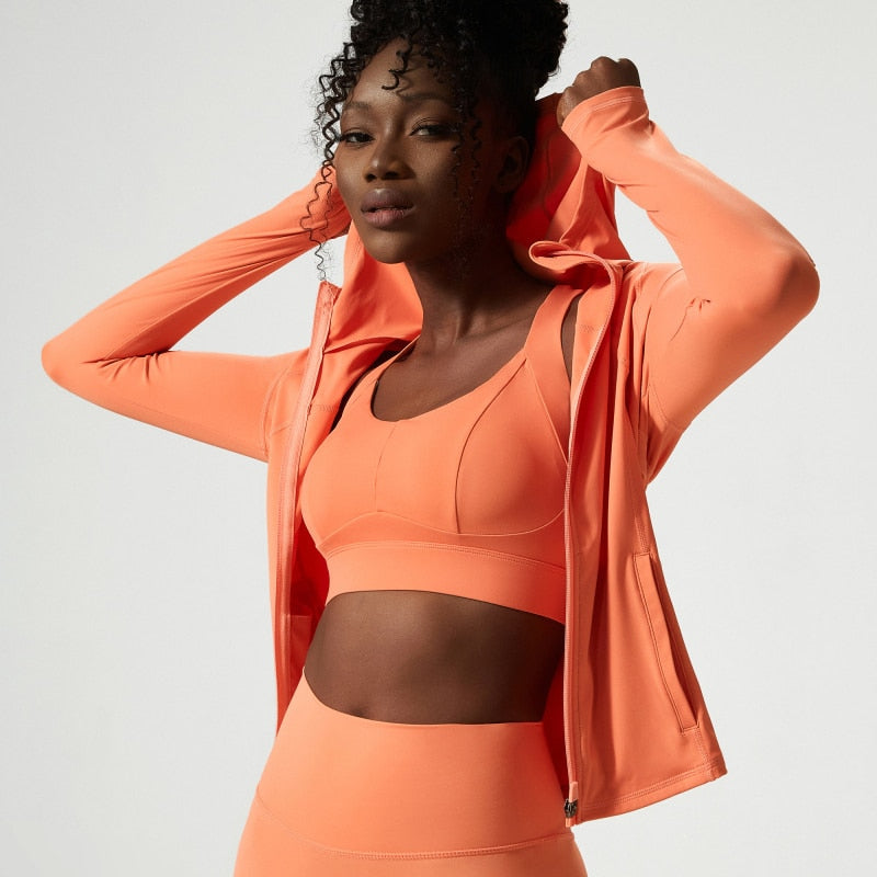 Women's hooded fitness jacket with long sleeves, thumb holes, and a workout design, ideal for yoga, running, and outdoor activities.