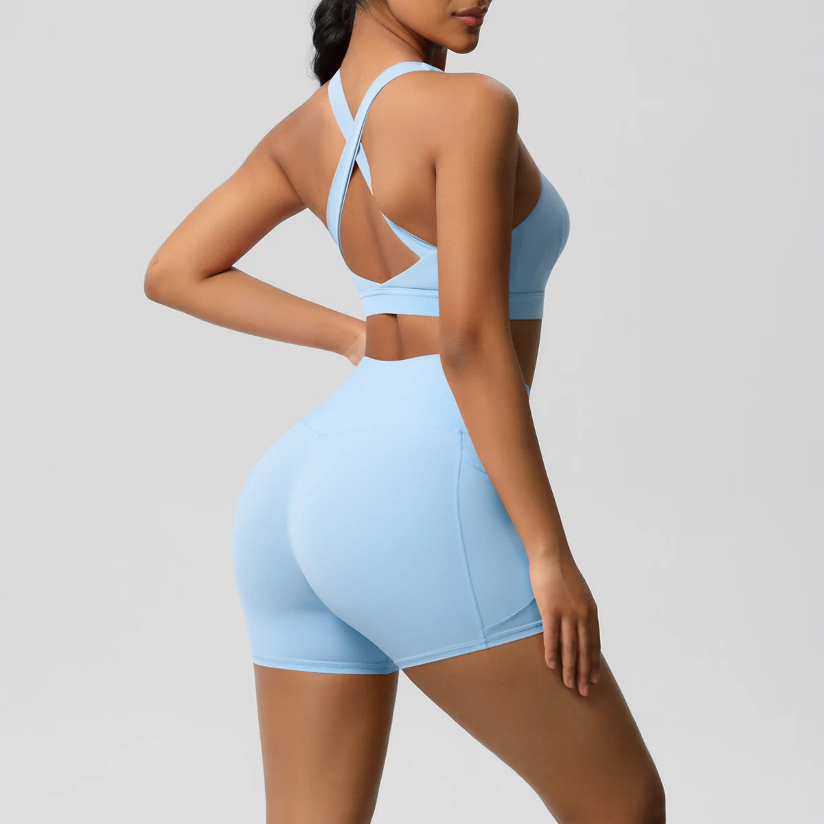 Black 2-piece sportswear yoga set with crossover bra and pocketed leggings, designed for women’s gym and fitness activities.
