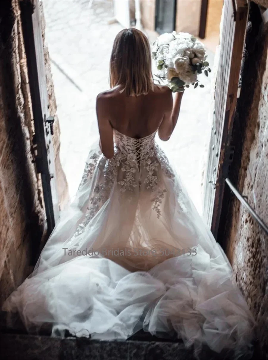 Customized strapless wedding dress with crystal lace appliques and flowing silhouette by The Clothing Company Sydney.