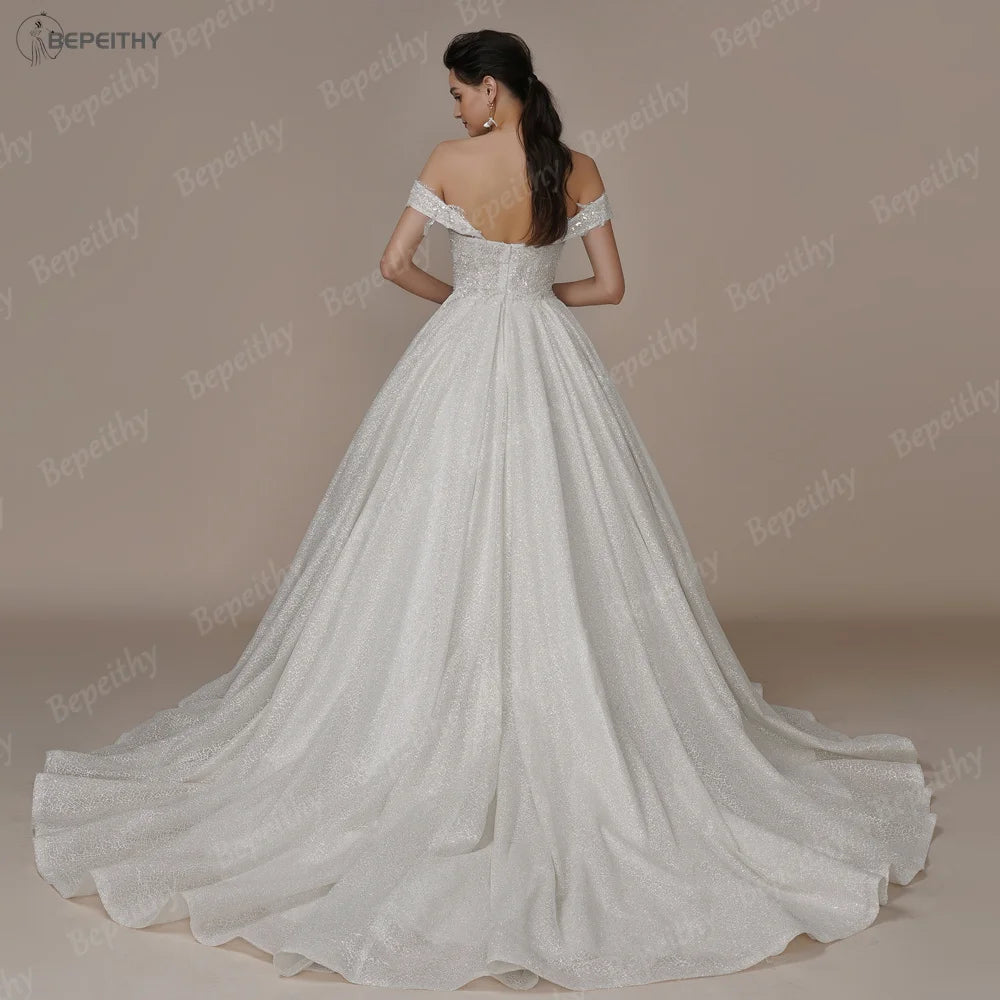 Elegant ivory strapless A-line wedding dress with glitter accents and off-the-shoulder design by The Clothing Company Sydney.