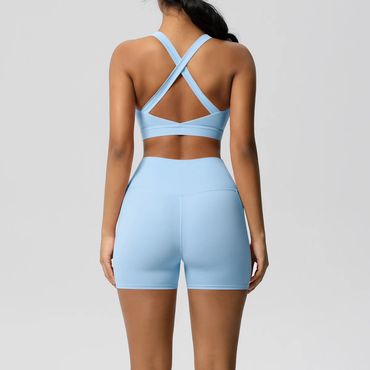 Two-piece women's fitness yoga set with crossover bra, pocketed gym shorts, and leggings, in stylish sportswear from The Clothing Company Sydney.