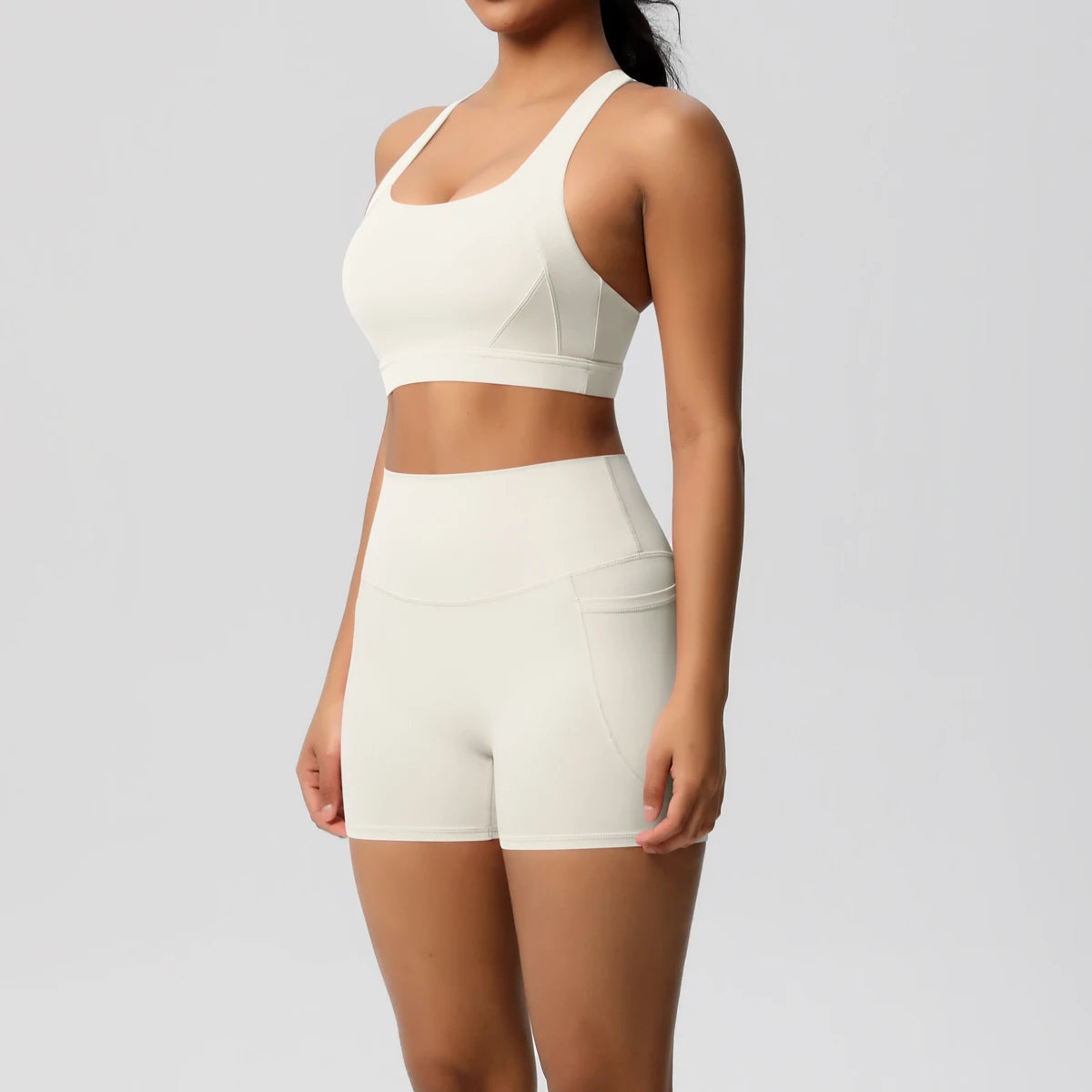 Two-piece women's sportswear yoga set by The Clothing Company Sydney with crossover bra, gym shorts, and leggings, featuring pockets.