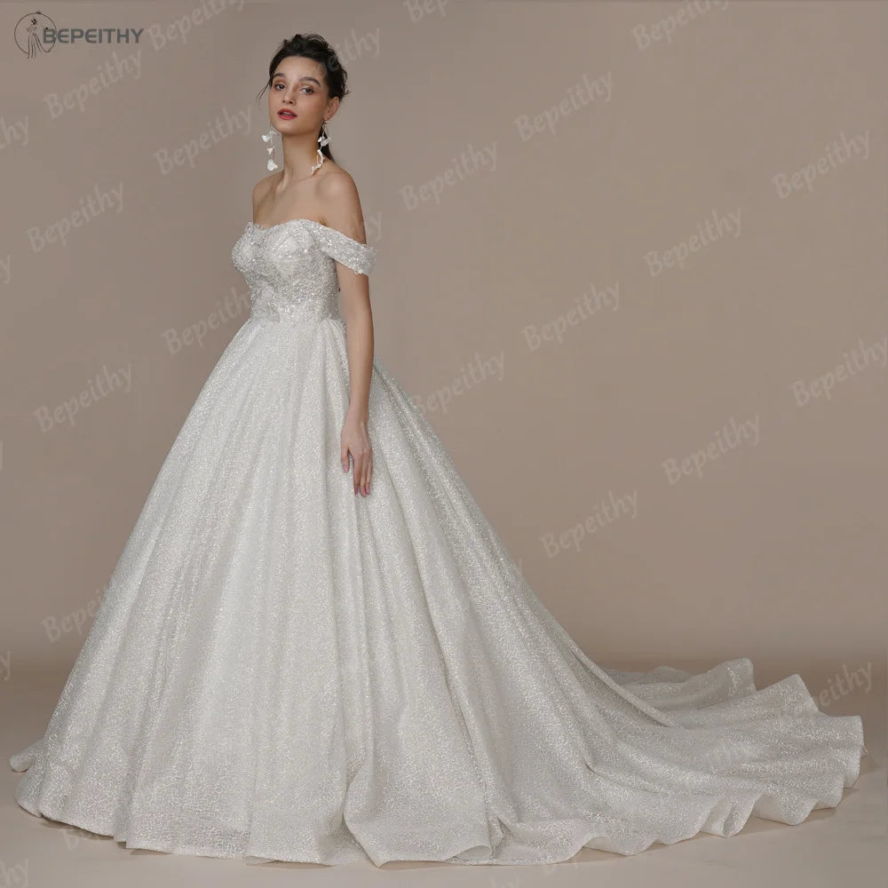 Elegant ivory strapless A-line wedding dress with glitter accents, off-the-shoulder design, by The Clothing Company Sydney.