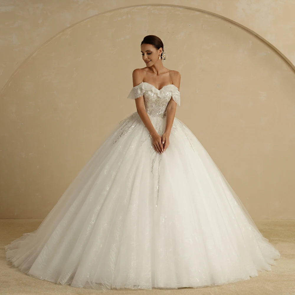 Ivory strapless A-line glitter wedding dress with off-the-shoulder design and bling details, designed for brides.