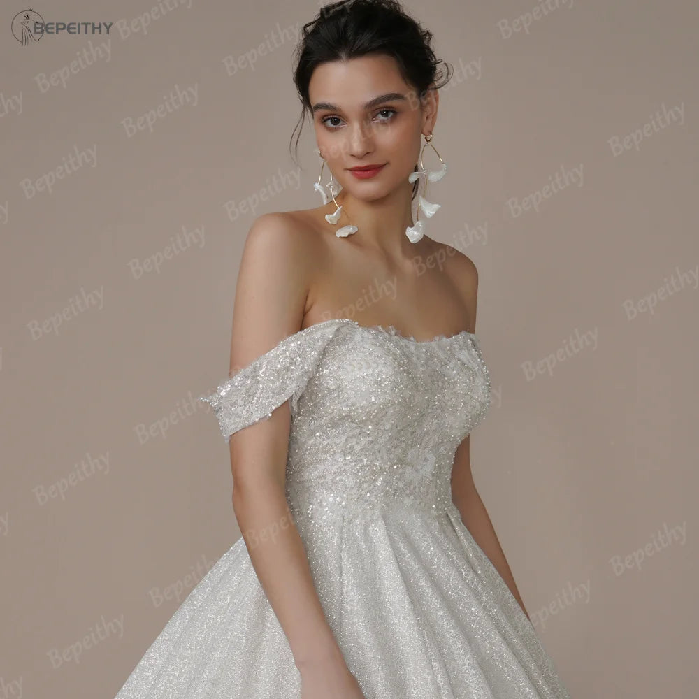 Ivory strapless A-line wedding dress with glitter accents, off-the-shoulder design, by The Clothing Company Sydney, bridal gown for brides
