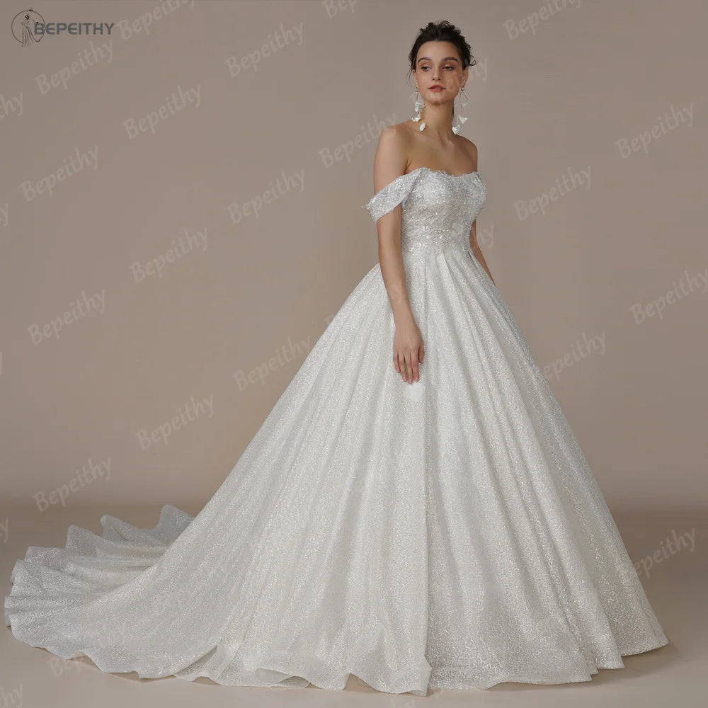 Elegant ivory strapless A-line wedding dress with glitter accents and off-the-shoulder design by The Clothing Company Sydney.