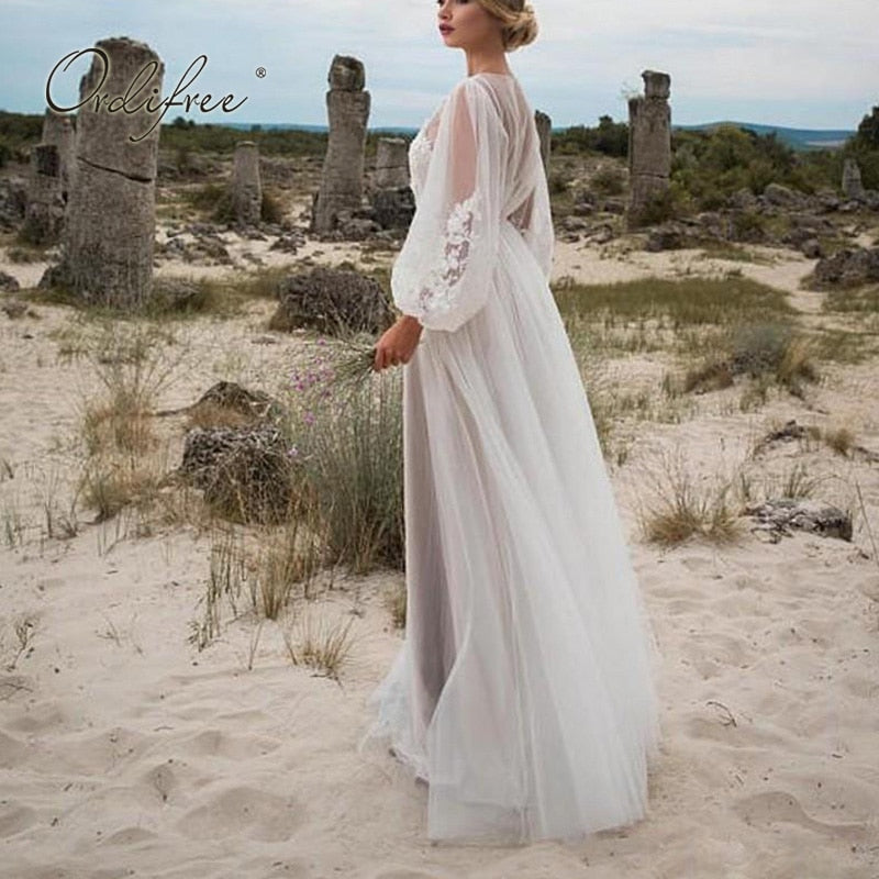 White long sleeve tulle wedding dress with embroidery, lace details, maxi length, suitable for summer vacations and beach wear.