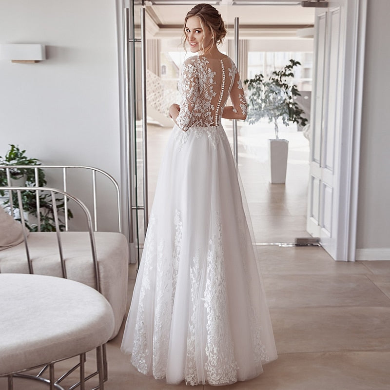 Elegant white wedding dress by The Clothing Company Sydney featuring lace appliques, tulle fabric, O-neck, button back, and half sleeves.
