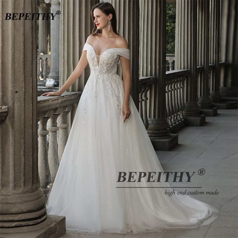 Ivory off-the-shoulder boho wedding dress with lace and beading, A-line silhouette, by The Clothing Company Sydney.