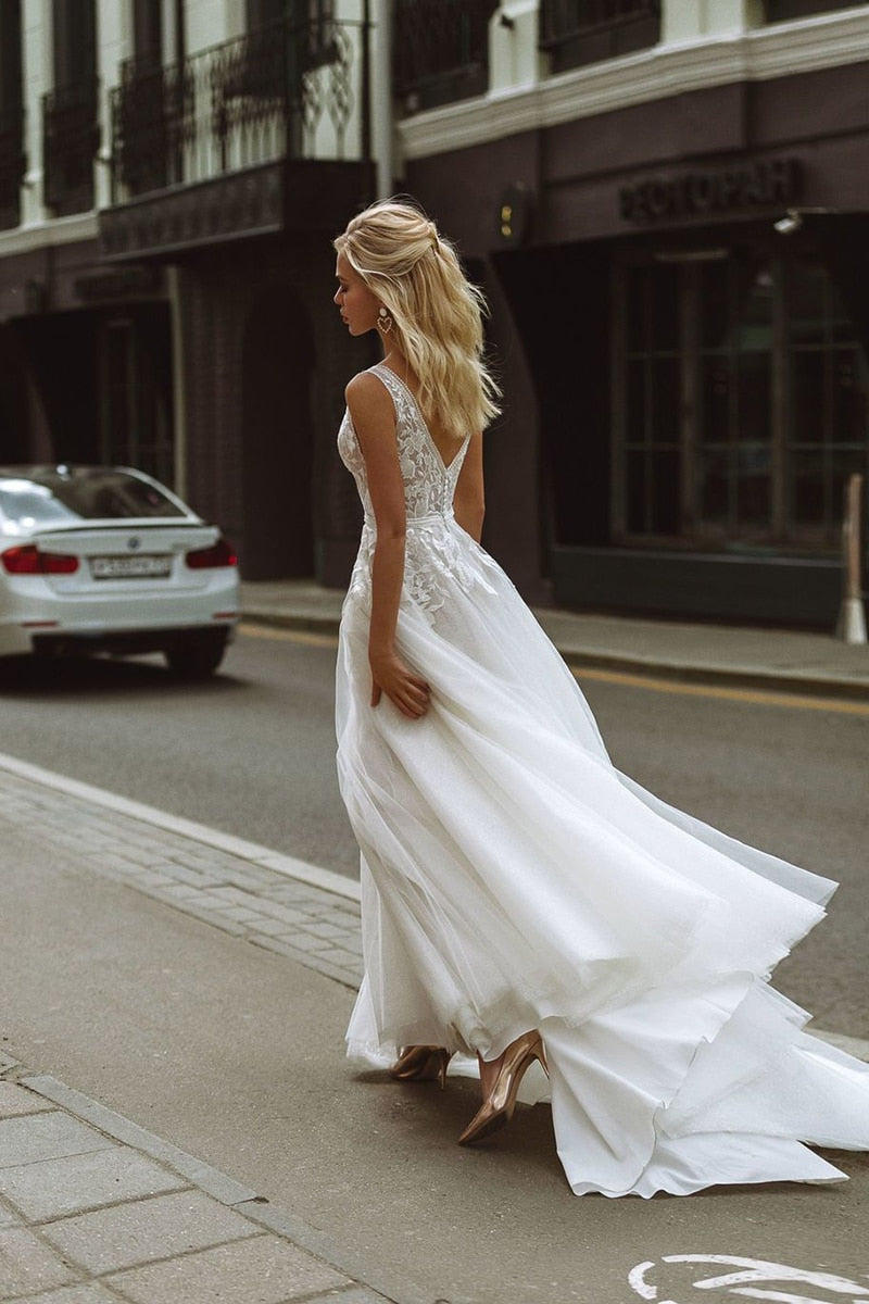 Boho wedding dress with deep V-neck, lace appliques, pearl buttons, tulle fabric, and A-line silhouette for beach bridal occasions.