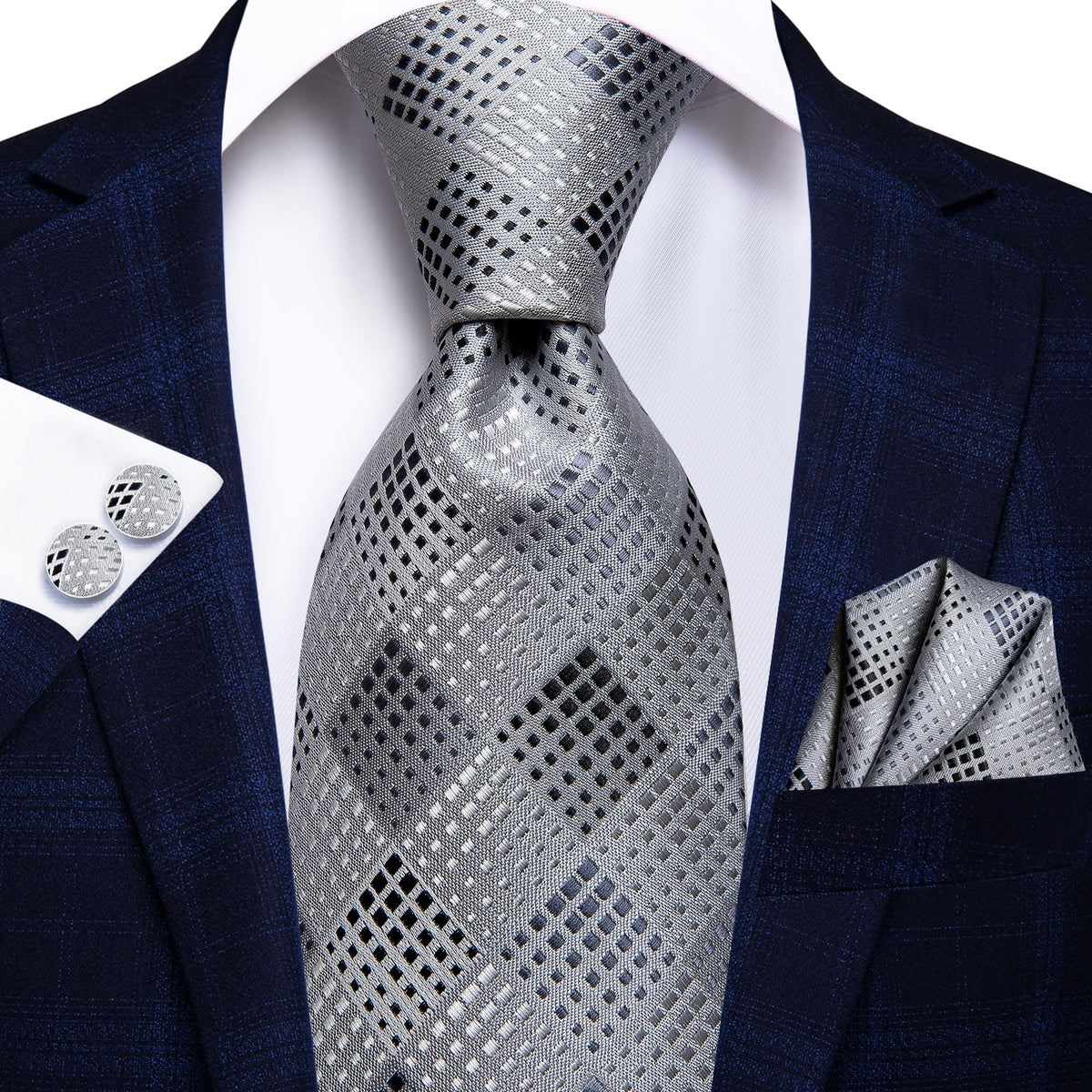 Three men's accessories including a solid paisley silk tie, cufflinks, and pocket square in a formal luxury style.