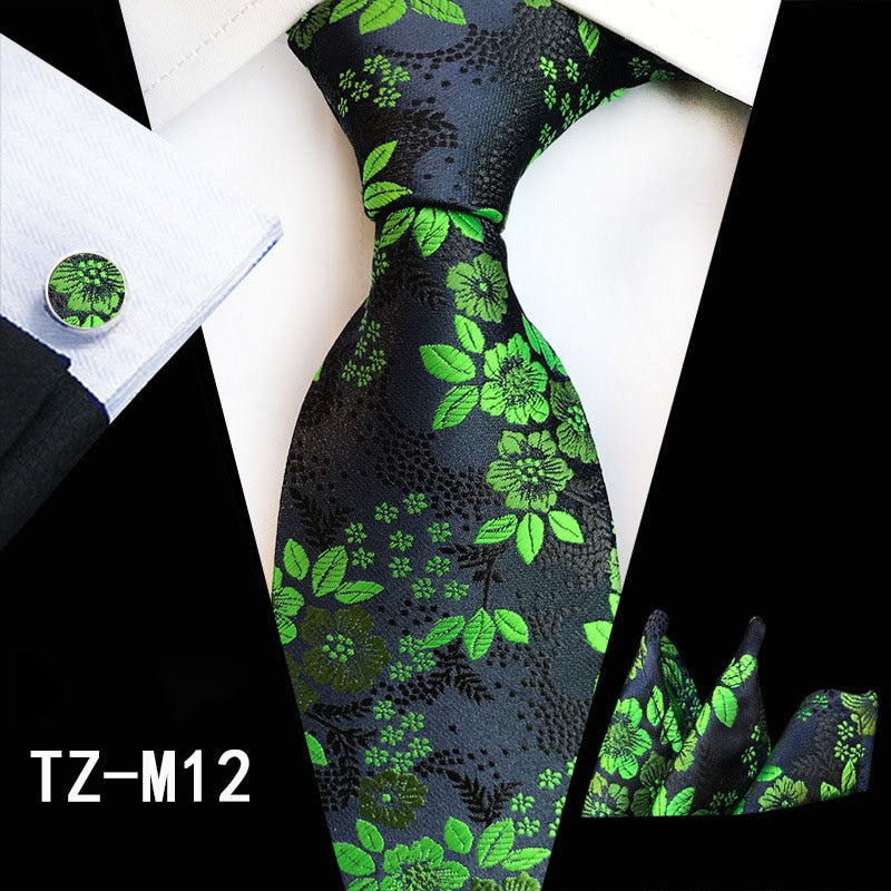 Red and green floral men's silk tie set with matching handkerchief, cufflinks, and necktie for business or wedding attire.