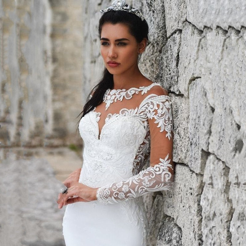 Elegant scoop neckline mermaid wedding dress with long sleeves, illusion back, lace appliqué, button details, and train.