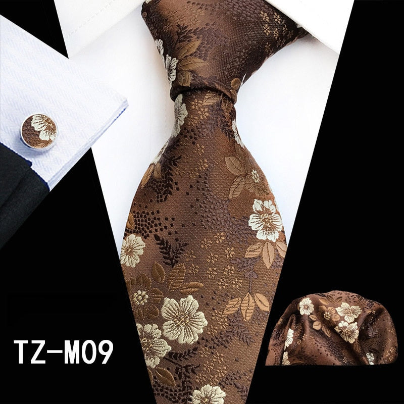 Red and green floral silk tie set with matching handkerchief and cufflinks, ideal for business or wedding attire.
