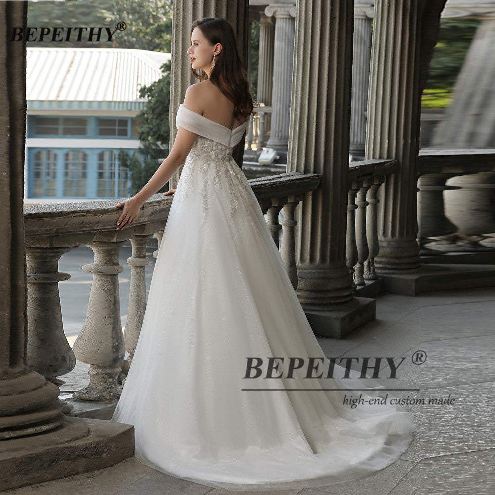 Ivory off-the-shoulder boho wedding dress by The Clothing Company Sydney featuring lace, beading, and an A-line silhouette.
