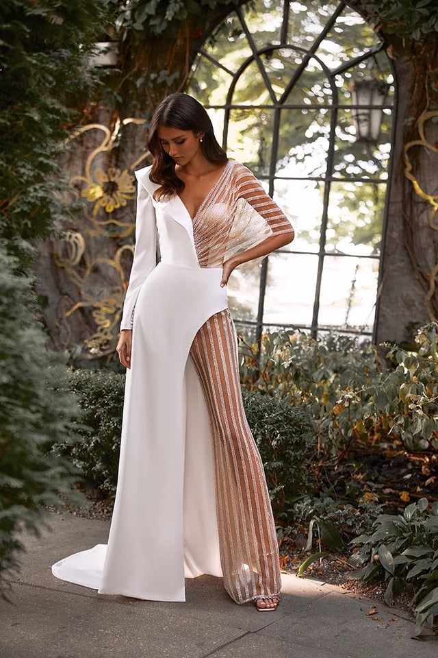 Elegant wedding jumpsuit by The Clothing Company Sydney featuring illusion tulle, long sleeves, V-neck, open back, and sweep train.