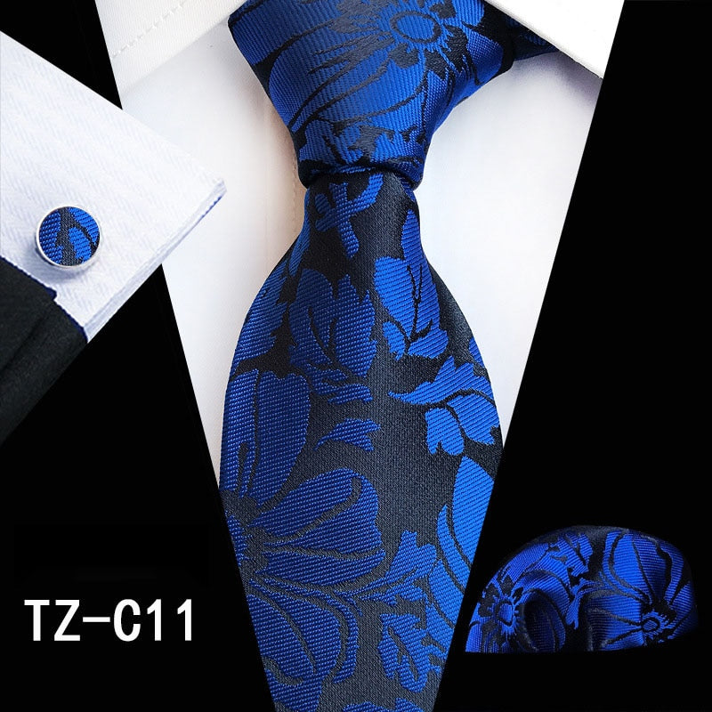 Men's silk tie set with red and green floral design, matching handkerchief, cufflinks, and necktie for business or wedding attire.