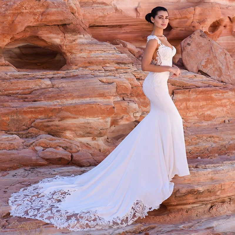 Satin mermaid wedding dress by The Clothing Company Sydney featuring boho sleeveless design, V-neck, beaded details, and long train.