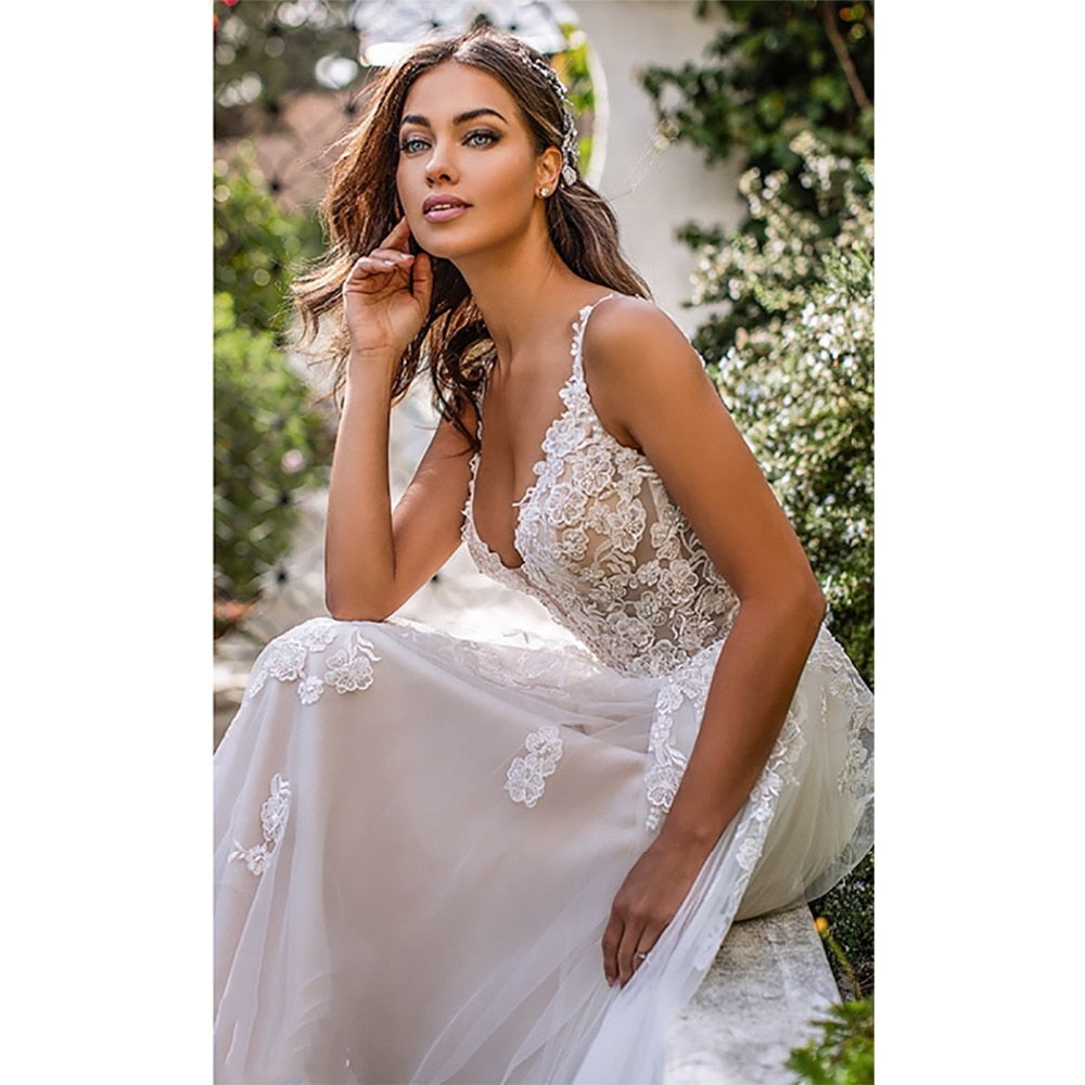 Long boho A-line wedding dress with 3D floral details, backless design, spaghetti straps, and floor-length gown for brides.