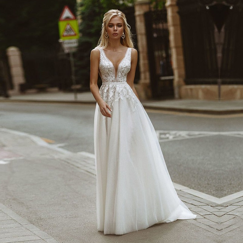 Boho wedding dress by The Clothing Company Sydney with deep V-neck, lace appliques, pearl buttons, A-line tulle gown, beach bridal style