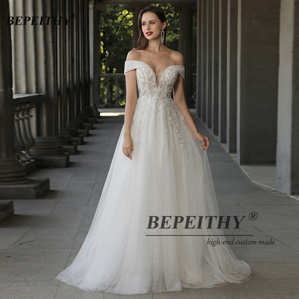 Off the shoulder ivory boho wedding dress with lace, beading, and A-line silhouette, designed for brides by The Clothing Company Sydney.