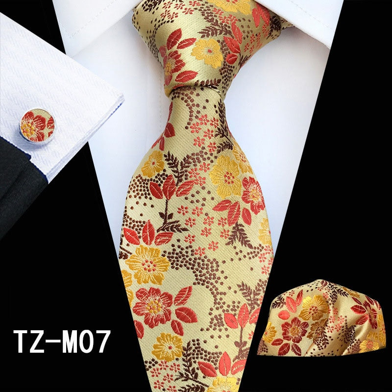 Red and green floral silk men's necktie set with matching handkerchief and cufflinks, suitable for business or wedding attire.