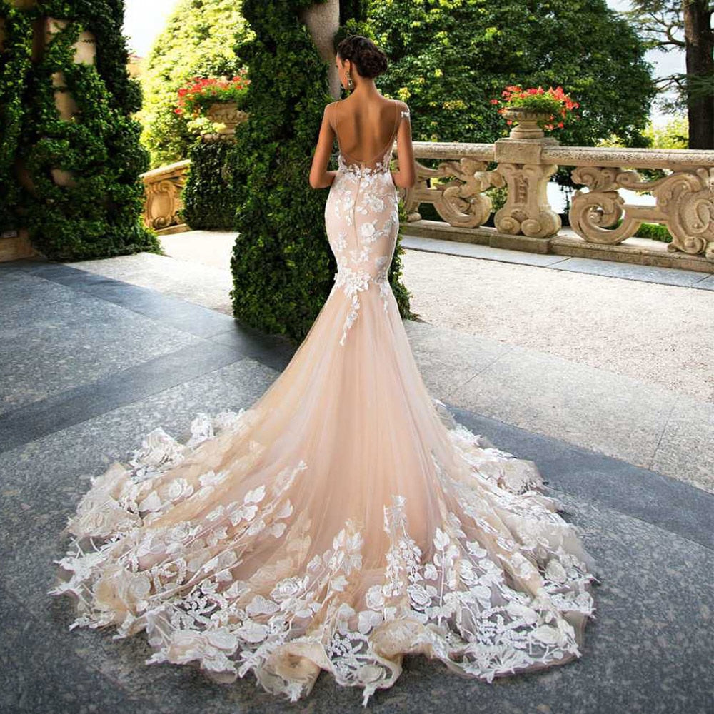 Elegant mermaid wedding dress with cap sleeves, backless design, floral appliques, and fitted silhouette from The Clothing Company Sydney.