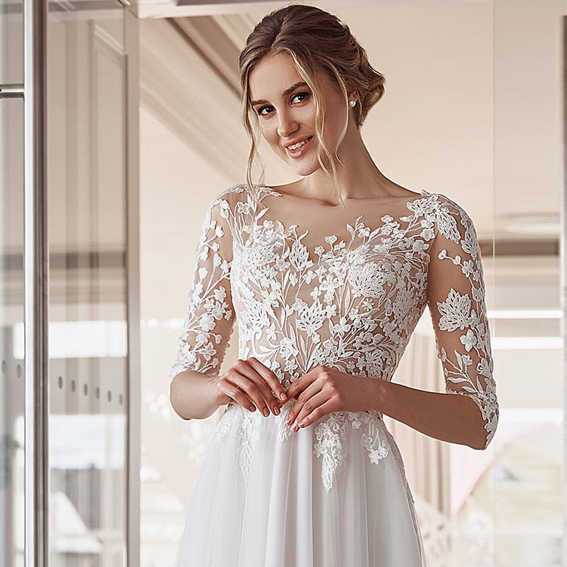 Floor length A-line wedding dress by The Clothing Company Sydney with lace appliques, O-neck, tulle, and button back detail.