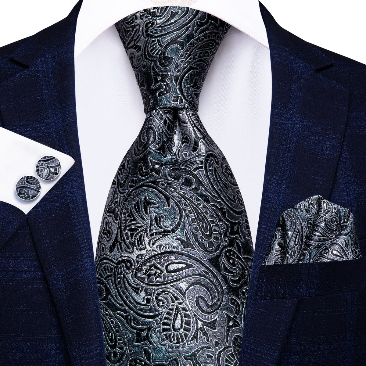 Three silk men's accessories including a paisley tie, cufflinks, and pocket square in elegant formal style.