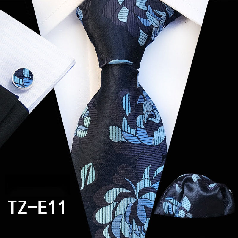 Men's silk tie set with red and green floral pattern, includes cufflinks, pocket square, and necktie for business or wedding attire.