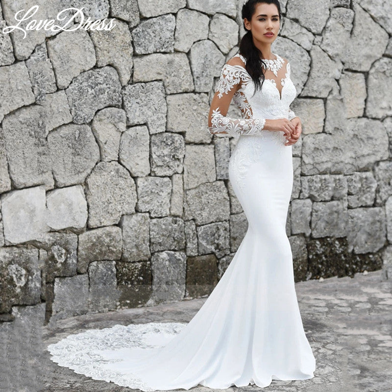 Elegant mermaid wedding dress by The Clothing Company Sydney with long sleeves, illusion back, lace appliqué, buttons, and train.