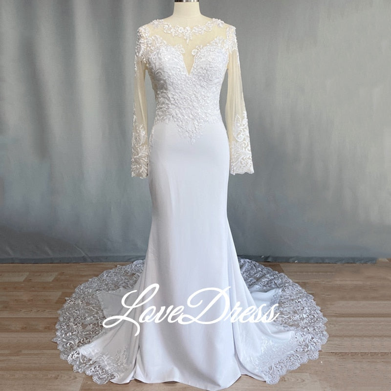Elegant scoop neck mermaid wedding dress with long sleeves, illusion back, lace appliqué, button details, and train from The Clothing Company Sydney.