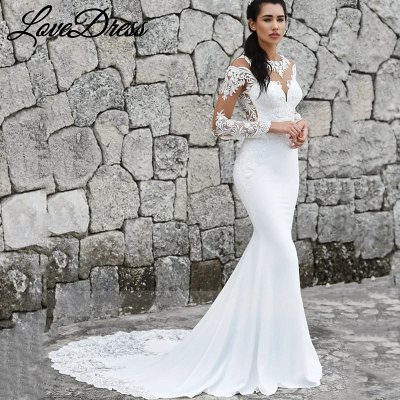 Elegant mermaid wedding dress with long sleeves, illusion back, lace appliqué, button details, and train by The Clothing Company Sydney.