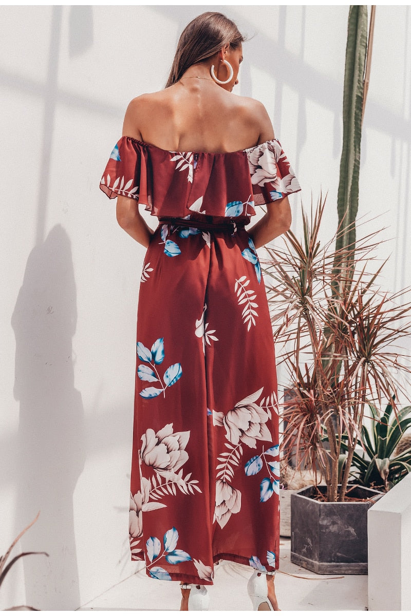 Bohemian floral print off-shoulder long jumpsuit with ruffled details and sashes, perfect for summer beach wear.
