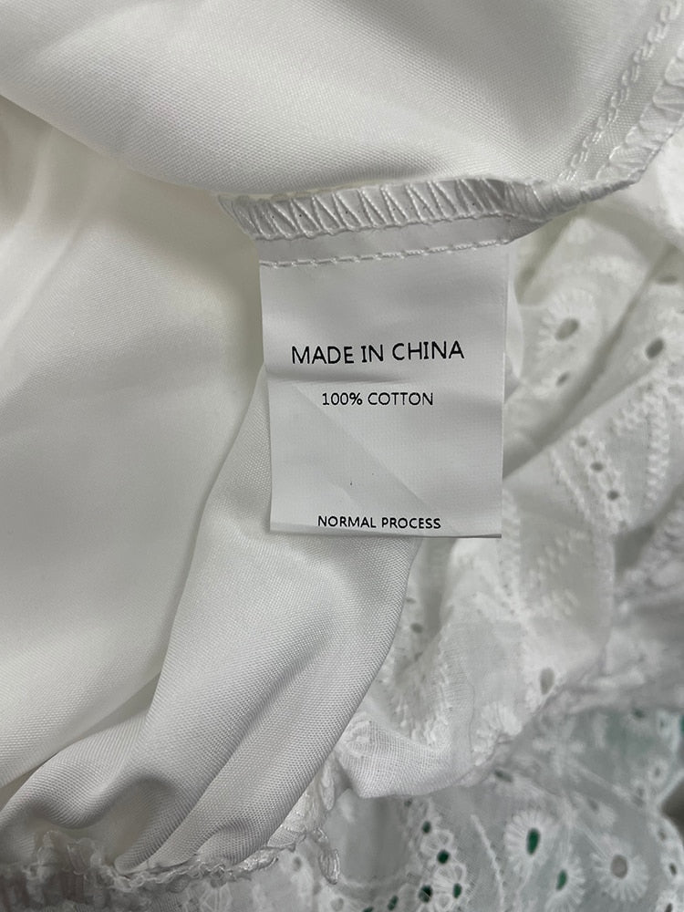 White cotton summer dress with lace-up front, ruffled hem, high waist, and A-line silhouette by The Clothing Company Sydney.