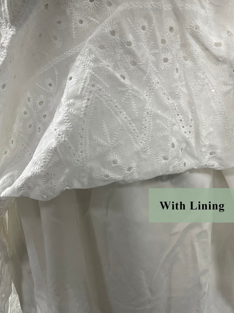 White cotton summer dress with lace-up front, hollow out design, high waist, ruffles, and A-line silhouette, casual holiday style.